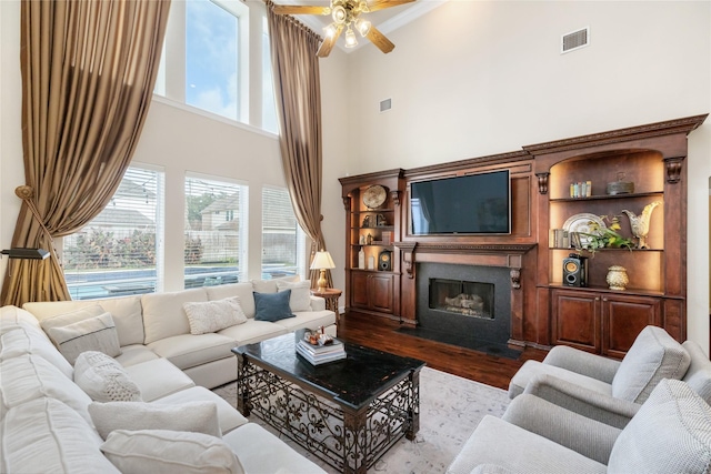 living room featuring hardwood / wood-style flooring, ceiling fan, and a high ceiling