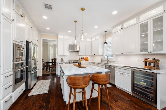 kitchen featuring wine cooler, a kitchen island, white cabinets, and appliances with stainless steel finishes