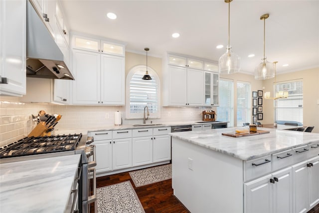 kitchen with a kitchen island, stainless steel range with gas cooktop, sink, white cabinets, and light stone countertops