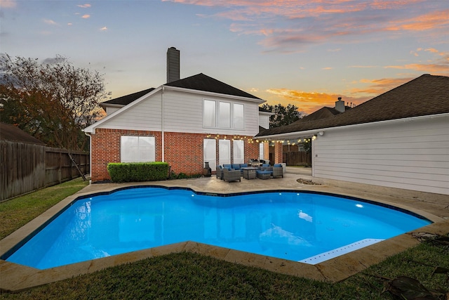 pool at dusk with outdoor lounge area and a patio area