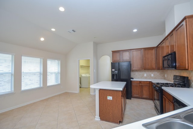 kitchen featuring a kitchen island, backsplash, lofted ceiling, light tile patterned floors, and black appliances