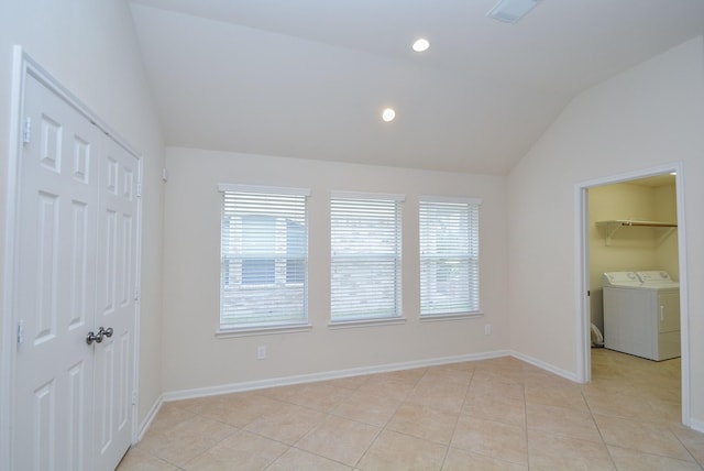 unfurnished bedroom with independent washer and dryer, light tile patterned flooring, lofted ceiling, and multiple windows