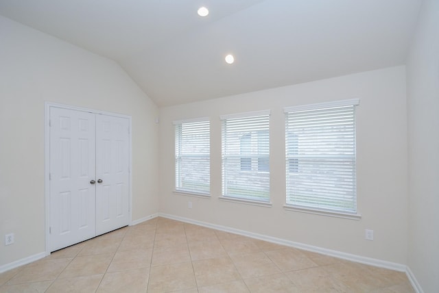 spare room featuring lofted ceiling and light tile patterned floors