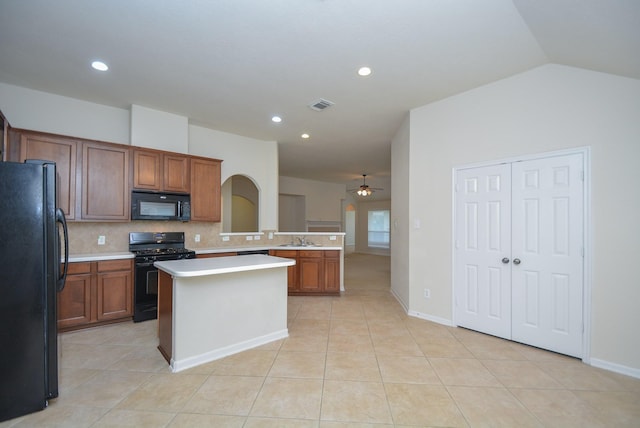 kitchen with a center island, lofted ceiling, black appliances, ceiling fan, and tasteful backsplash