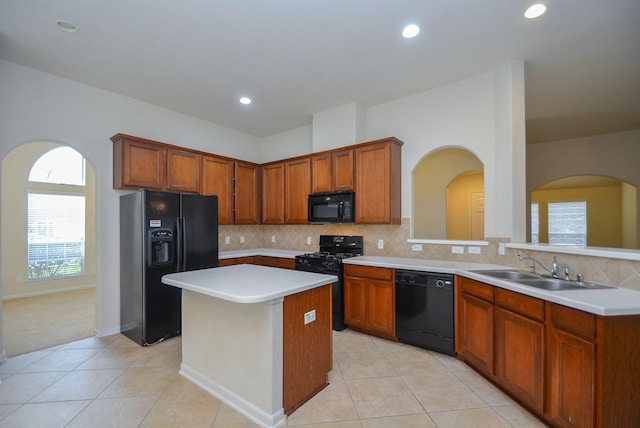 kitchen with a center island, black appliances, sink, decorative backsplash, and light tile patterned floors