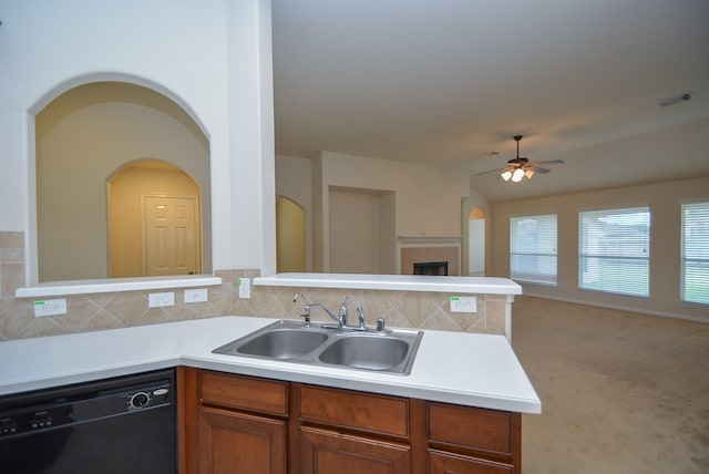 kitchen featuring tasteful backsplash, a tiled fireplace, sink, and black dishwasher