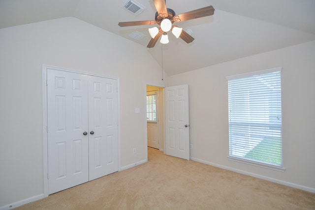 unfurnished bedroom featuring ceiling fan, a closet, light carpet, and lofted ceiling