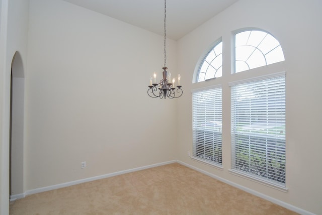 carpeted spare room with a notable chandelier