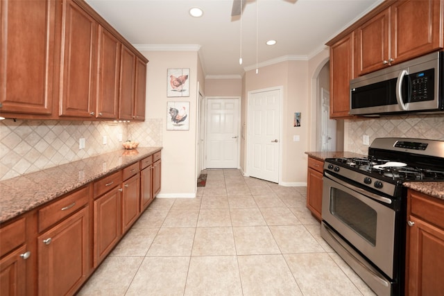 kitchen featuring light tile patterned floors, light stone countertops, ornamental molding, and appliances with stainless steel finishes