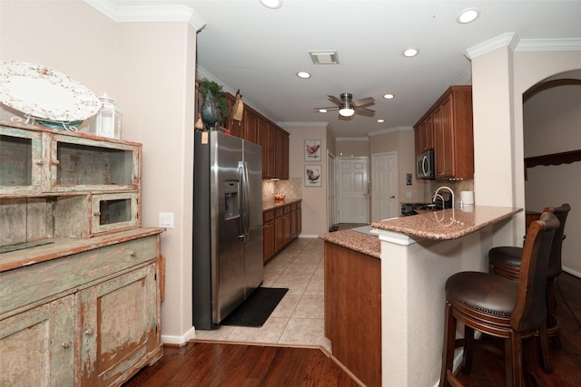 kitchen featuring a breakfast bar area, crown molding, ceiling fan, and appliances with stainless steel finishes