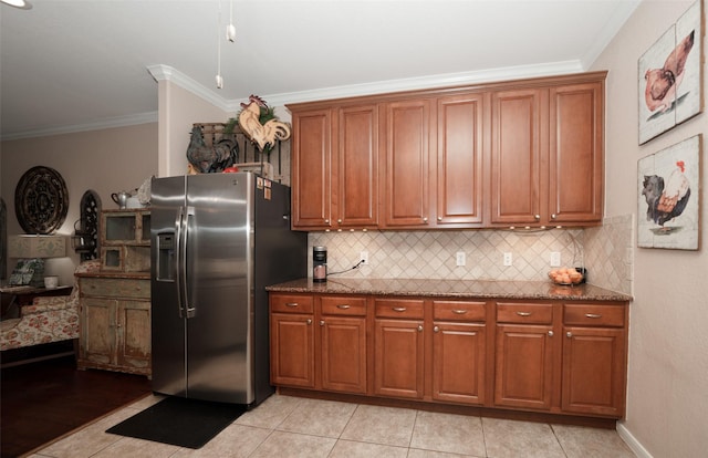 kitchen with backsplash, crown molding, stainless steel fridge, dark stone countertops, and light tile patterned flooring