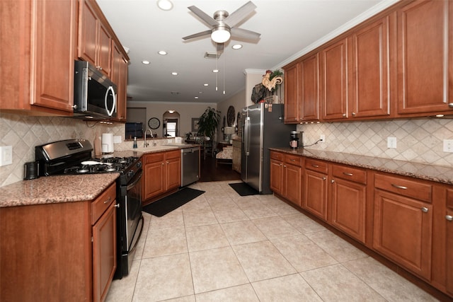 kitchen with sink, ceiling fan, light tile patterned flooring, light stone counters, and stainless steel appliances