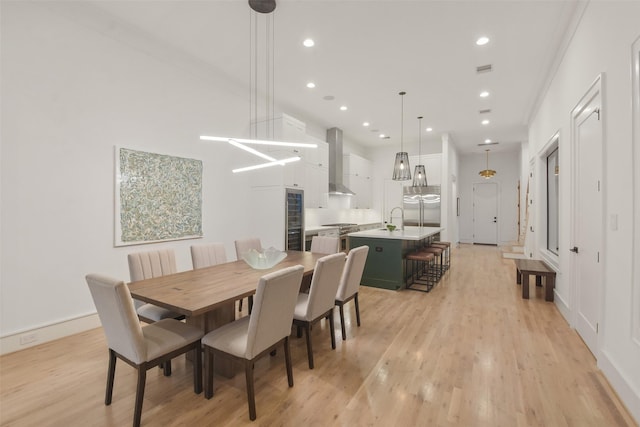 dining area with crown molding, sink, and light hardwood / wood-style floors