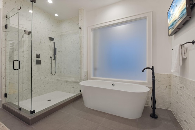 bathroom with tile patterned flooring, plus walk in shower, and tile walls