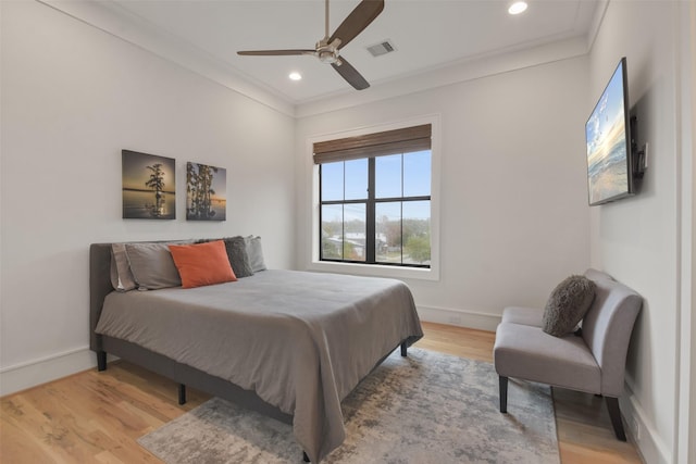 bedroom featuring ceiling fan, ornamental molding, and light wood-type flooring