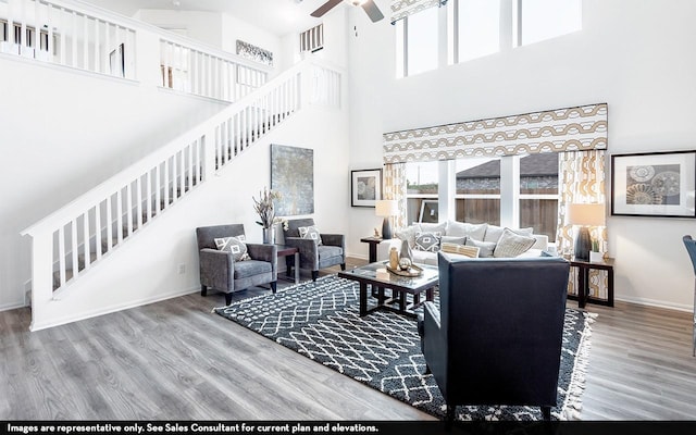 living room with a high ceiling, ceiling fan, and wood-type flooring