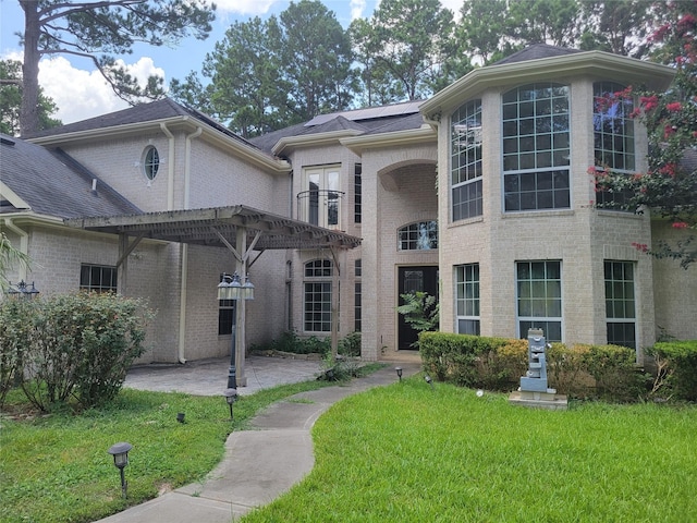 view of front of house featuring solar panels, a pergola, a patio, and a front yard