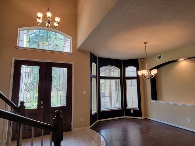 tiled foyer entrance with a healthy amount of sunlight, a textured ceiling, and an inviting chandelier