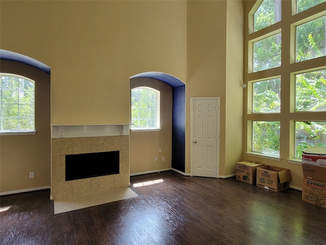 unfurnished living room featuring dark hardwood / wood-style floors, a towering ceiling, and a fireplace