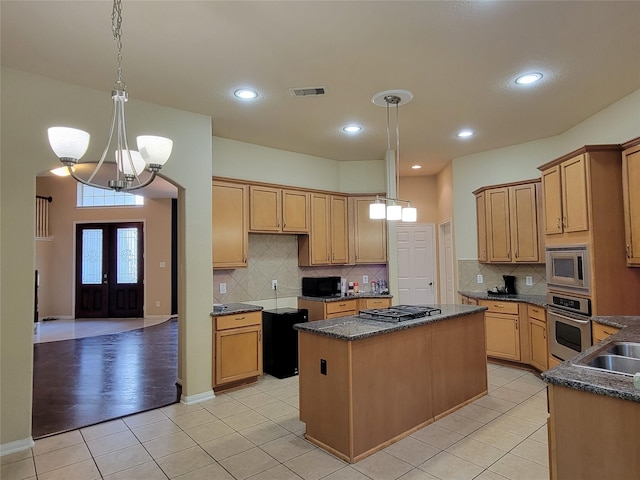 kitchen with stainless steel appliances, a kitchen island, a chandelier, pendant lighting, and light tile patterned flooring