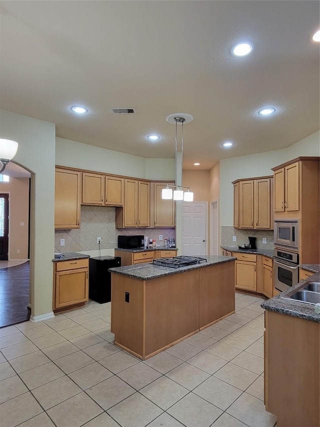 kitchen featuring appliances with stainless steel finishes, sink, pendant lighting, a center island, and light tile patterned flooring