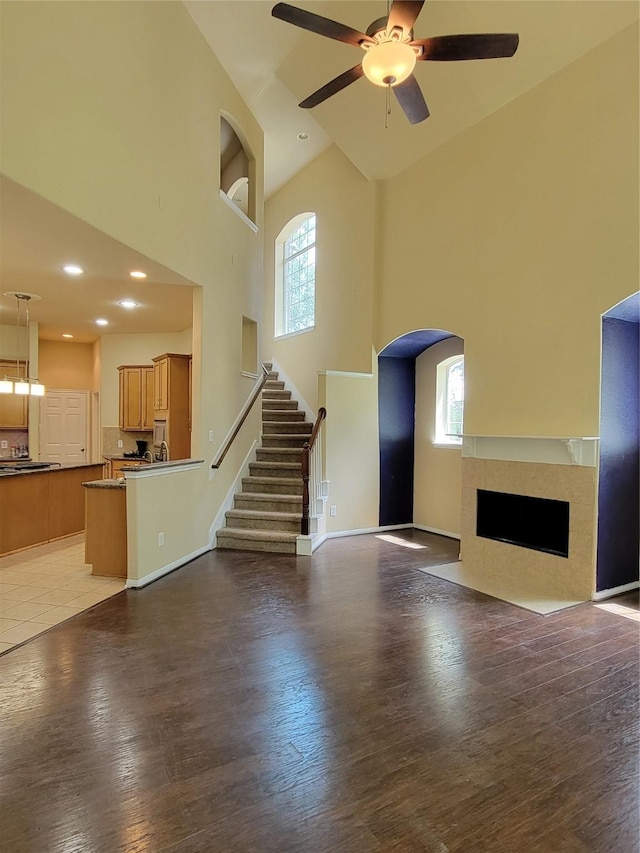 unfurnished living room featuring a tiled fireplace, ceiling fan, and dark hardwood / wood-style flooring