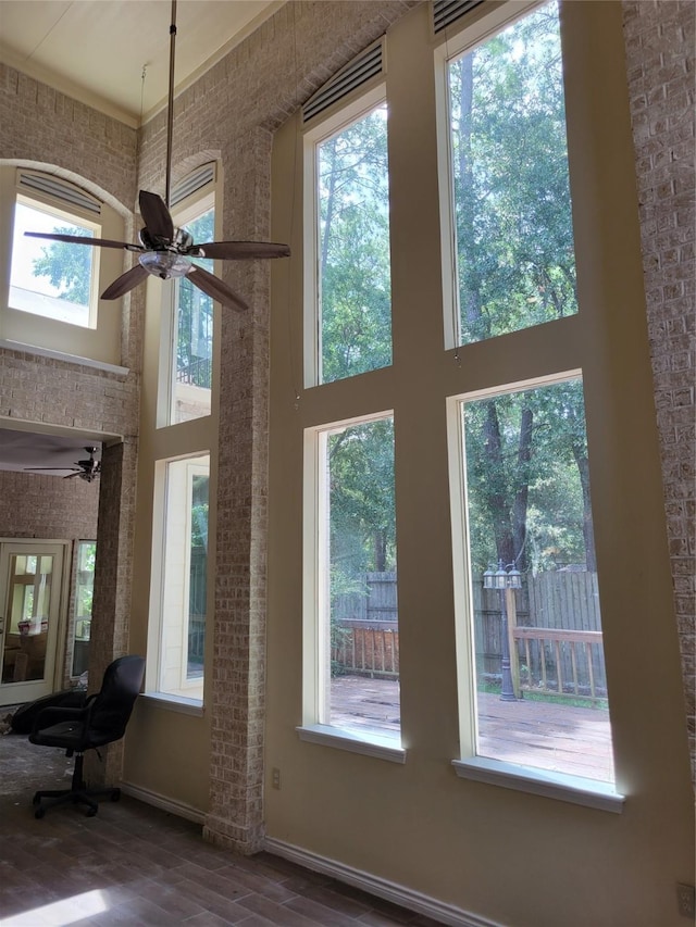 interior space featuring a high ceiling, a wealth of natural light, and brick wall