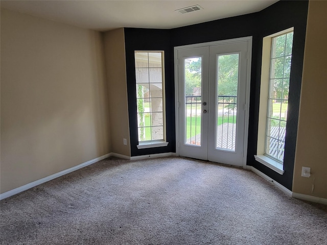 carpeted spare room featuring french doors