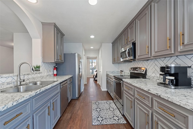 kitchen with dark hardwood / wood-style floors, stainless steel appliances, decorative backsplash, gray cabinets, and sink