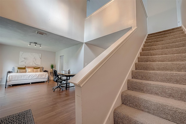 stairs with rail lighting and hardwood / wood-style flooring