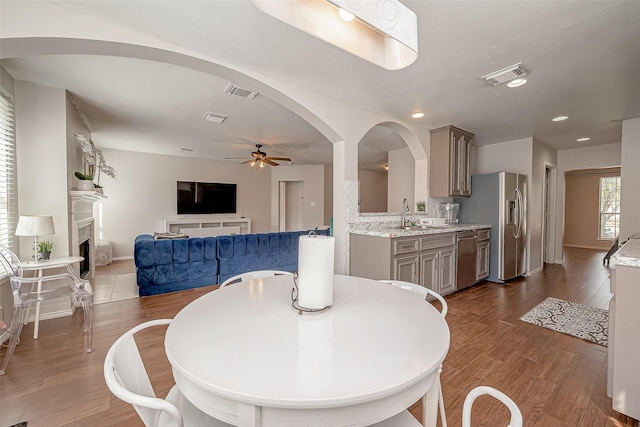 dining area with sink, ceiling fan, and dark wood-type flooring