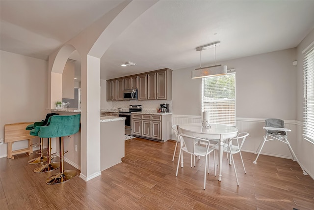 kitchen featuring stainless steel appliances, hardwood / wood-style flooring, decorative backsplash, and pendant lighting