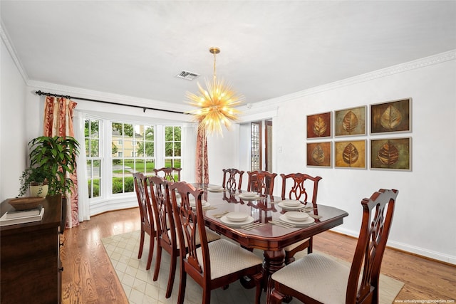 dining area with crown molding, a chandelier, and light hardwood / wood-style floors