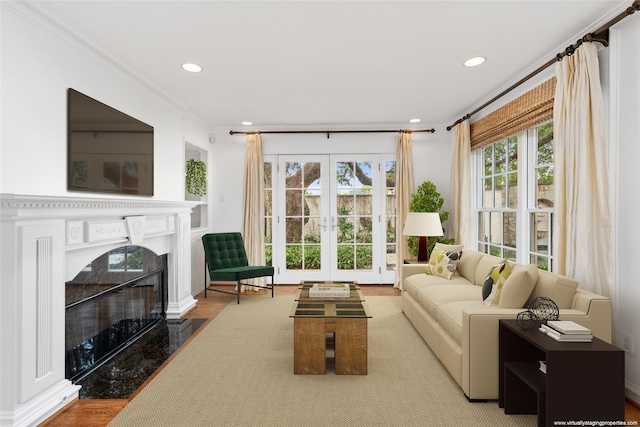 living room with hardwood / wood-style floors, a premium fireplace, crown molding, and french doors