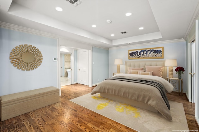 bedroom featuring wood-type flooring, a raised ceiling, and crown molding