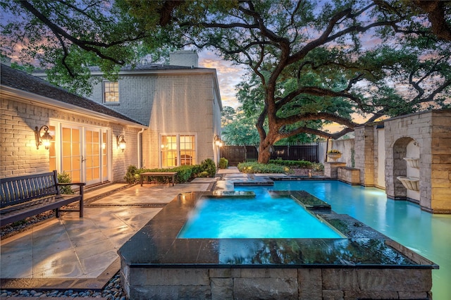 pool at dusk featuring a patio area