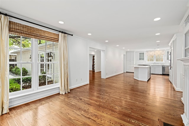 unfurnished living room featuring light hardwood / wood-style flooring, ornamental molding, and sink