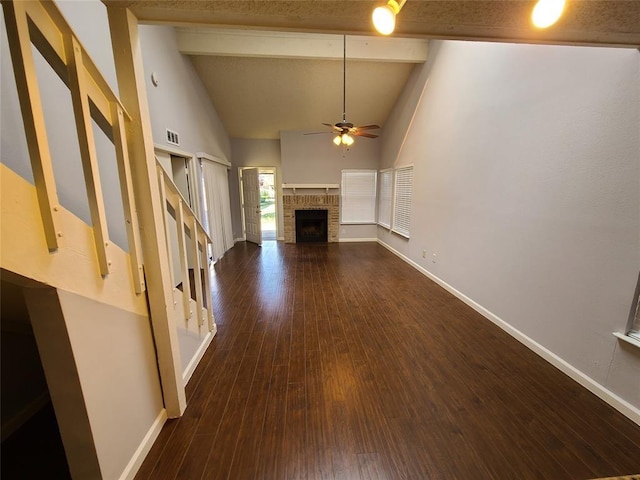 unfurnished living room with beam ceiling, ceiling fan, a stone fireplace, high vaulted ceiling, and dark hardwood / wood-style floors