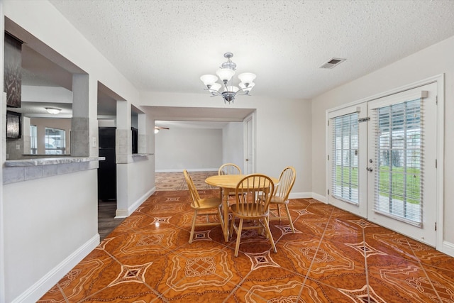 dining space with tile patterned floors, a textured ceiling, an inviting chandelier, and french doors