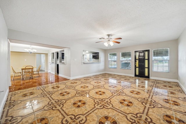 unfurnished living room with a textured ceiling, tile patterned floors, and ceiling fan with notable chandelier