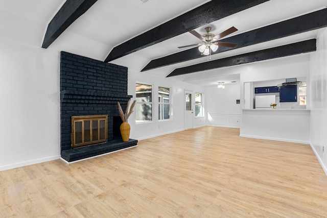 unfurnished living room featuring beamed ceiling, hardwood / wood-style floors, a brick fireplace, and ceiling fan