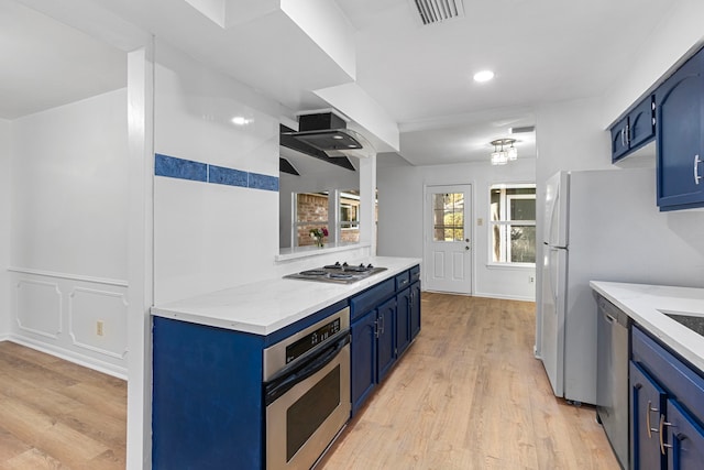 kitchen with light hardwood / wood-style floors, blue cabinetry, and appliances with stainless steel finishes