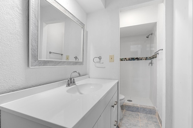 bathroom with tiled shower, vanity, and toilet