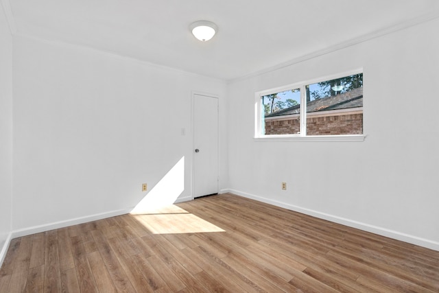 empty room with light hardwood / wood-style flooring and crown molding