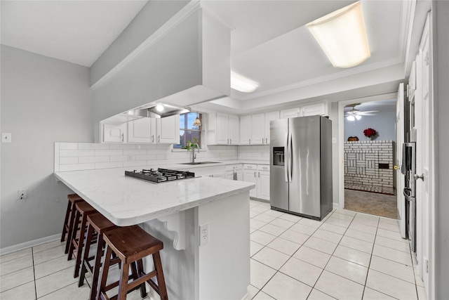 kitchen featuring white cabinetry, a kitchen bar, ceiling fan, tasteful backsplash, and stainless steel refrigerator with ice dispenser