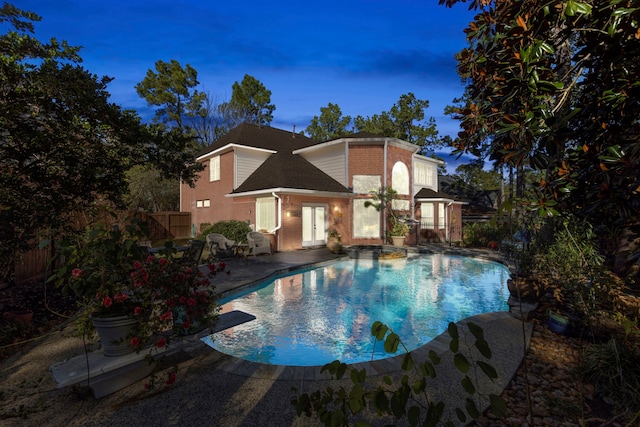 pool at dusk with a patio area and french doors