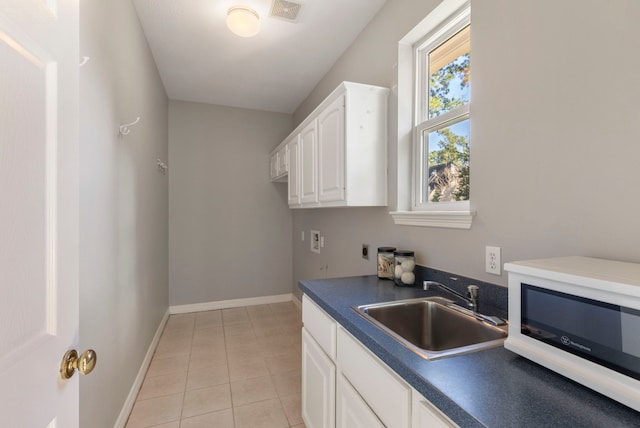 kitchen with white cabinets, light tile patterned floors, and sink