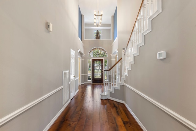 entrance foyer with dark hardwood / wood-style flooring, a towering ceiling, french doors, and a notable chandelier