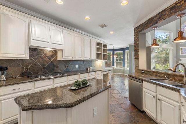 kitchen with stainless steel appliances, sink, decorative light fixtures, white cabinets, and a center island