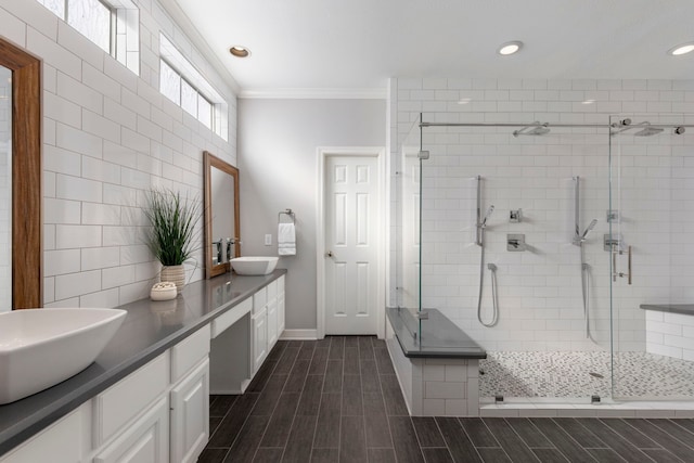 bathroom featuring vanity, a shower with shower door, and ornamental molding